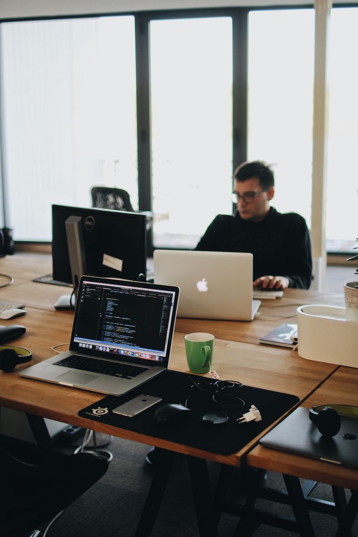 our-story A web developer working on code in a modern office setting with multiple devices.